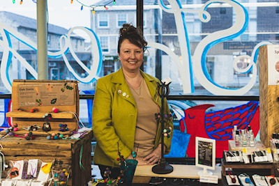 Lisa June Byers posing for a photo behind her vendor table at the Guelph Farmers’ Market   